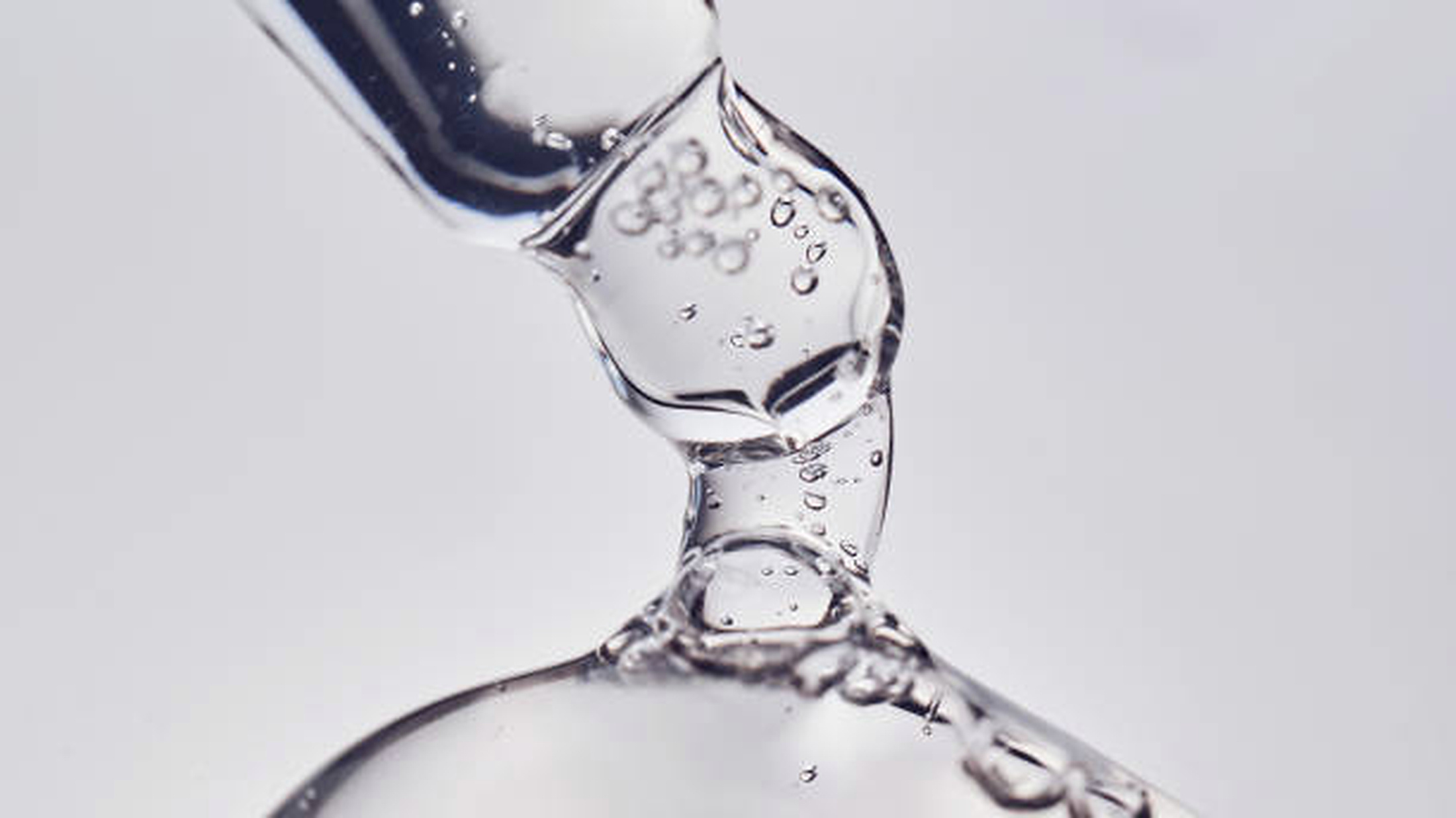 Pipet serum membiaskan cahaya pada latar putih bersih